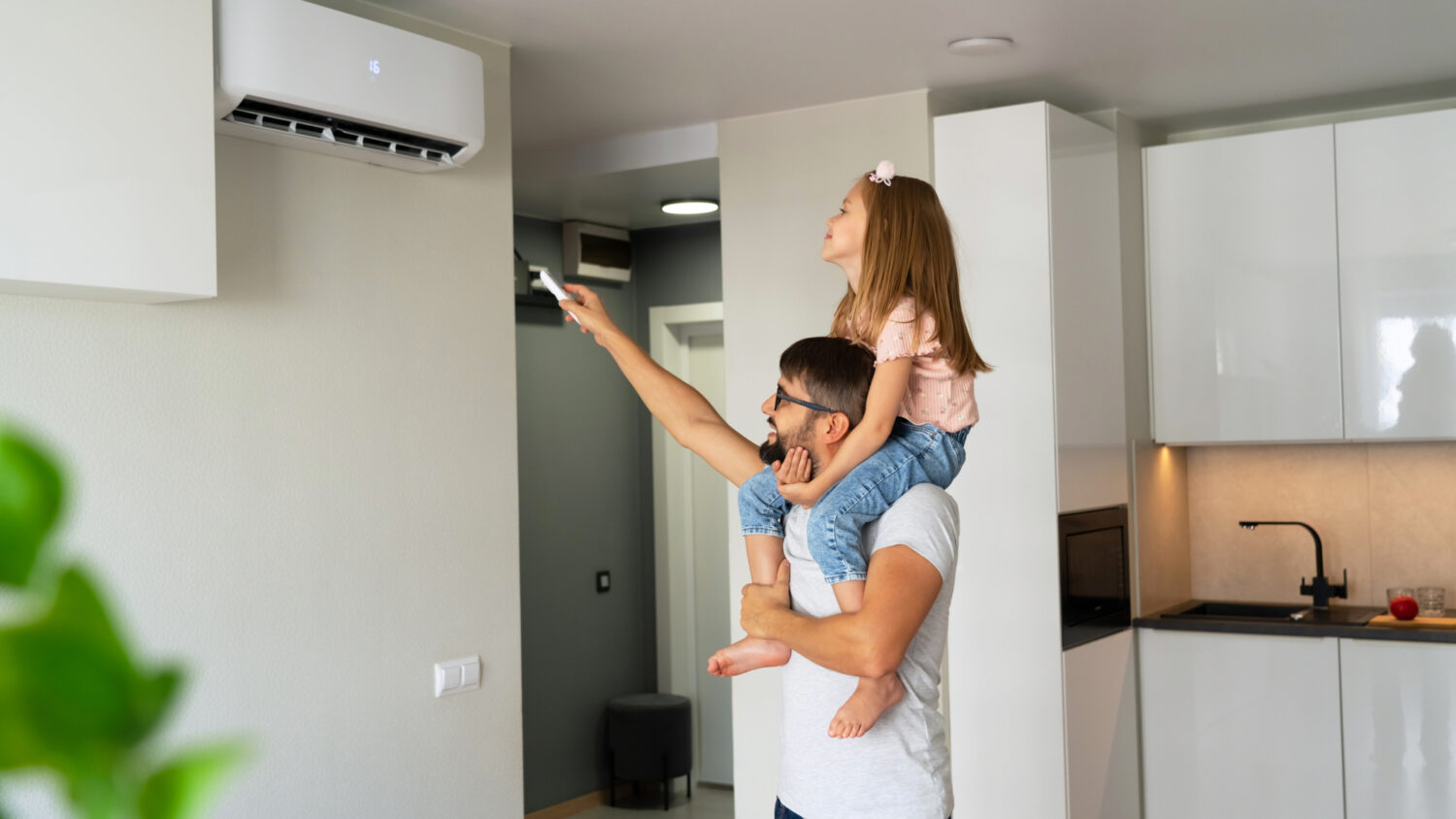 Father with daughter on shoulders turn on air conditioner using remote control